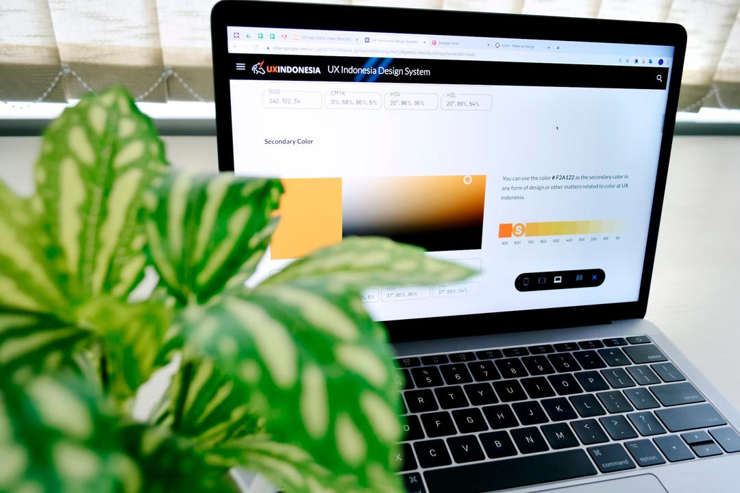 A plant in the front with a laptop behind it doing research after color