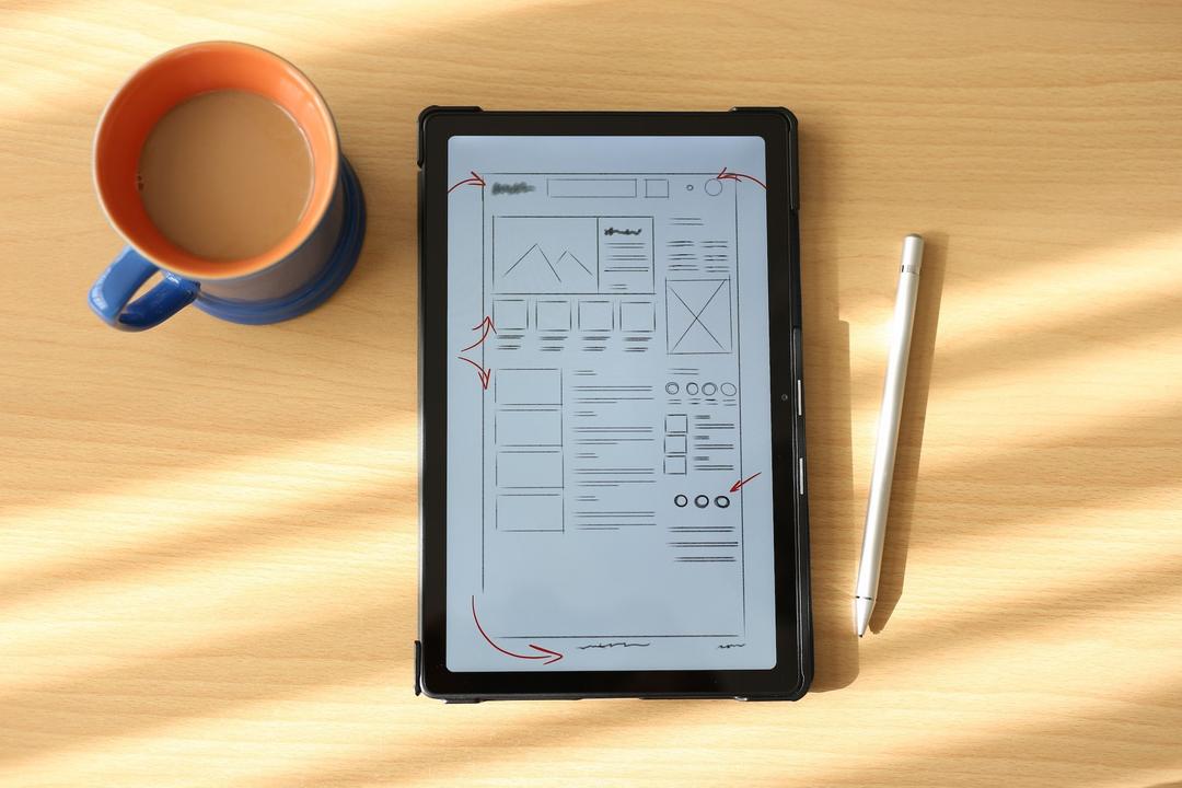 Tablet with wireframes on table with a cup of coffee next to it